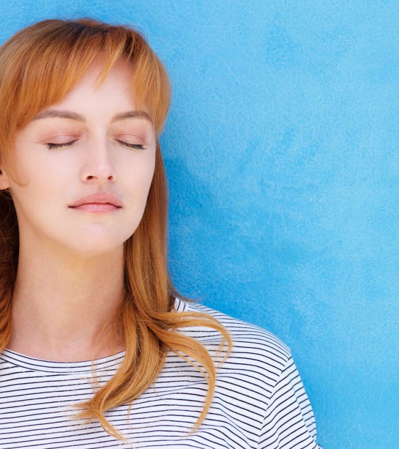 Young red hair woman with eyes closed Close up portrait of serious woman standing with eyes closed in contemplation